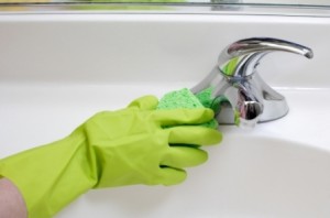 A person cleaning the bathroom sink with a glove